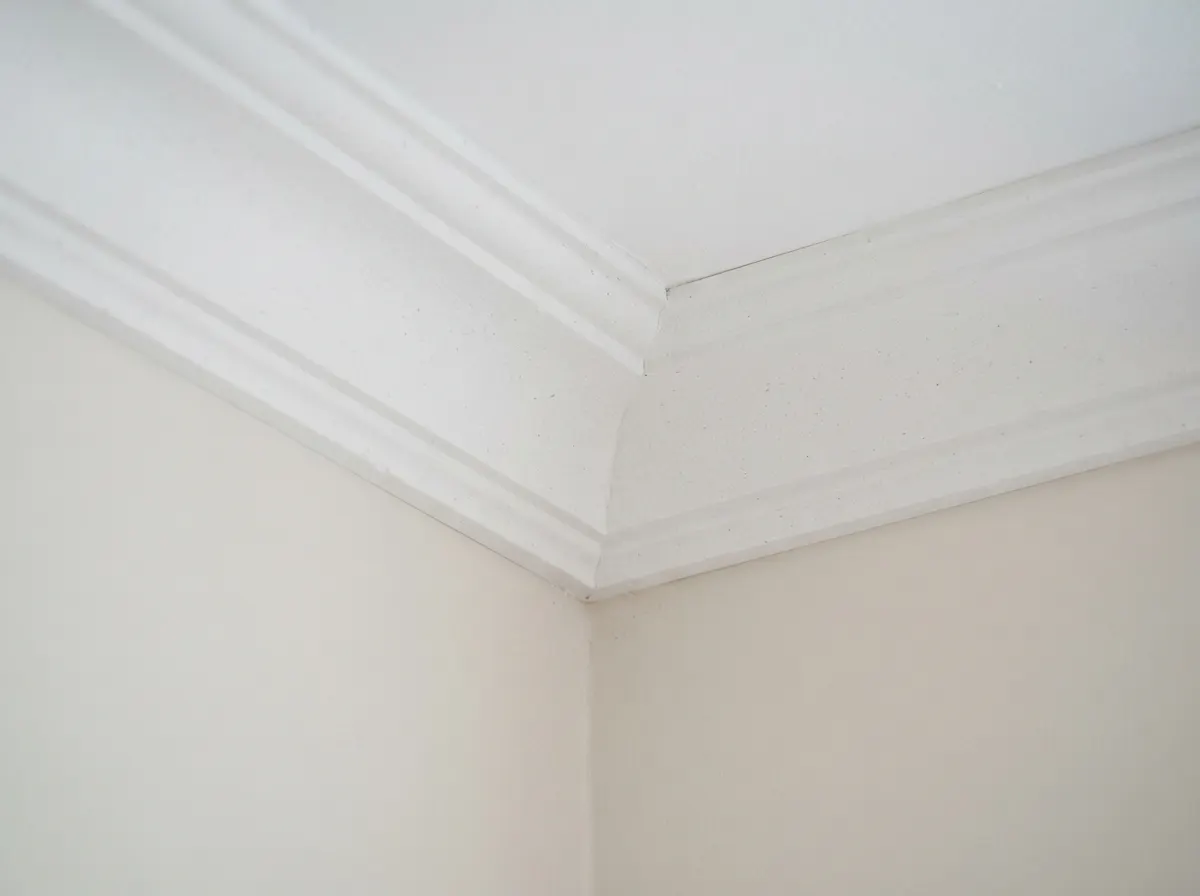A decorator installing modern stepped duropolymer coving along the ceiling of a newly painted living room